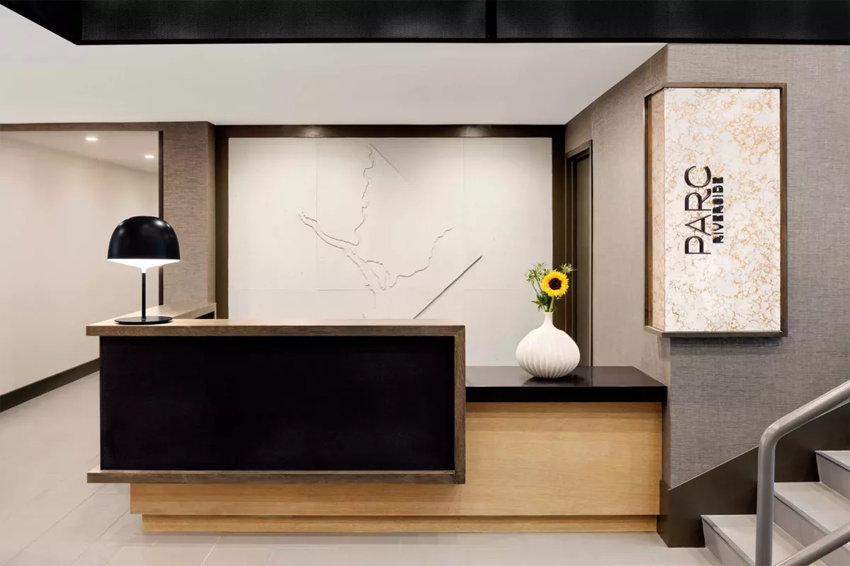 Lobby reception desk with minimalist decor, wall art, and soft accent lighting.