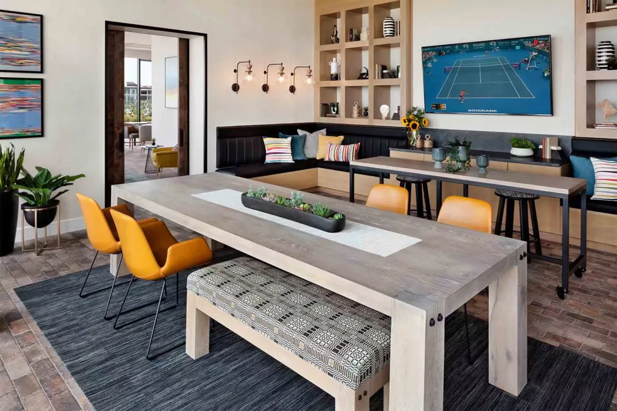 Communal lounge with shuffleboard table, seating, and floor‑to‑ceiling windows.