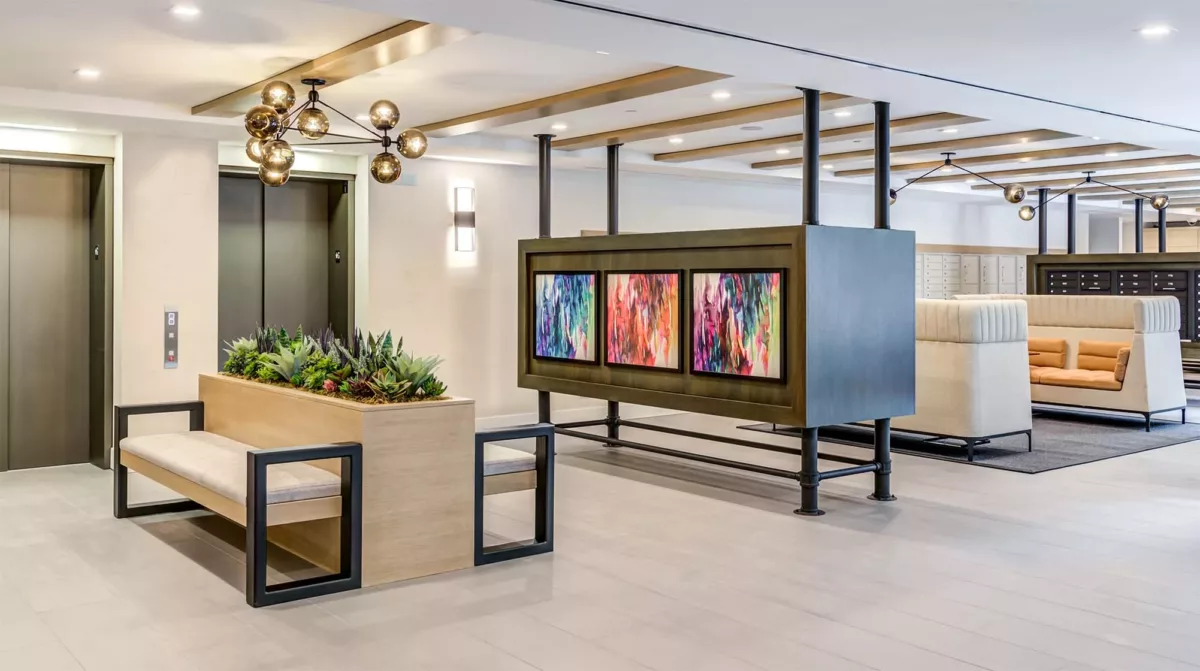 Resident lounge with artwork divider, seating areas, planters, and polished floors.