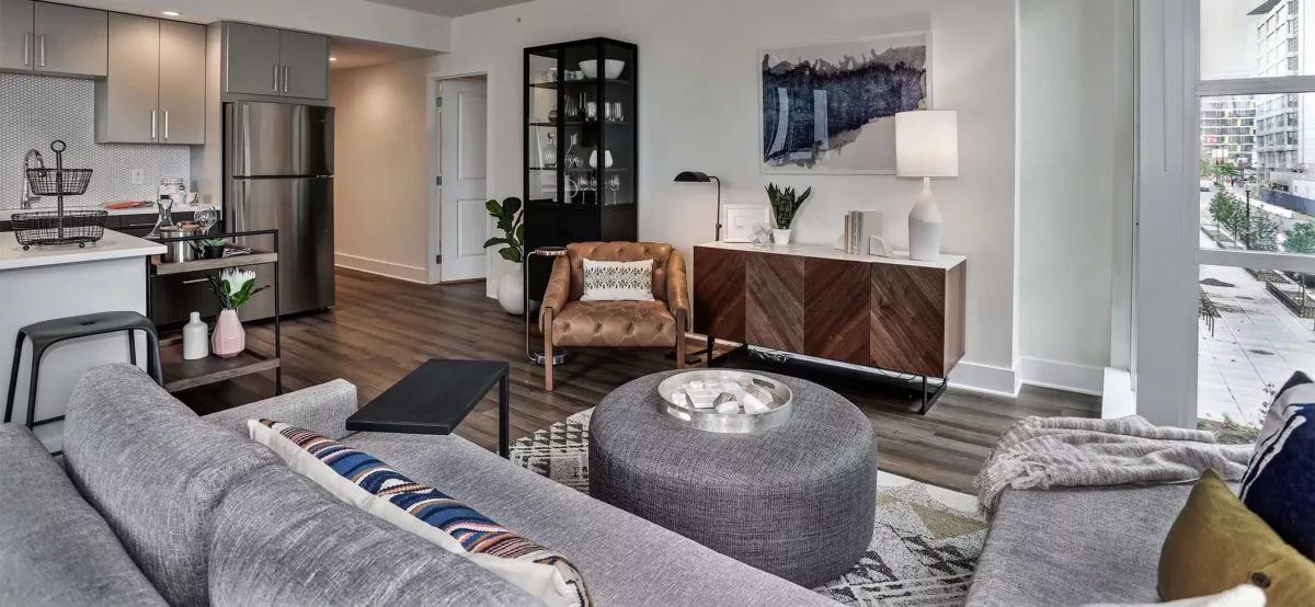 Open living room with sectional sofa, accent chair, media console, and kitchen beyond.