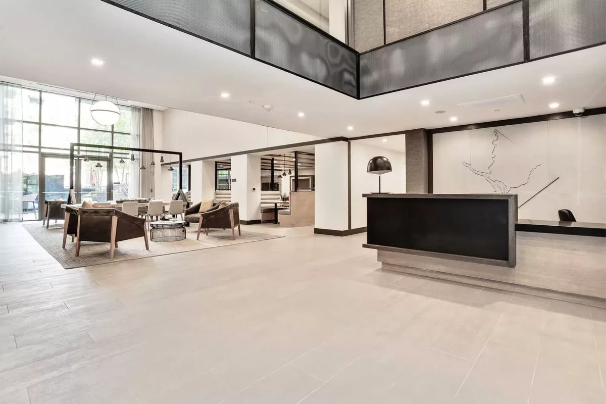 Modern apartment lobby with seating areas, high ceilings, and polished floors.
