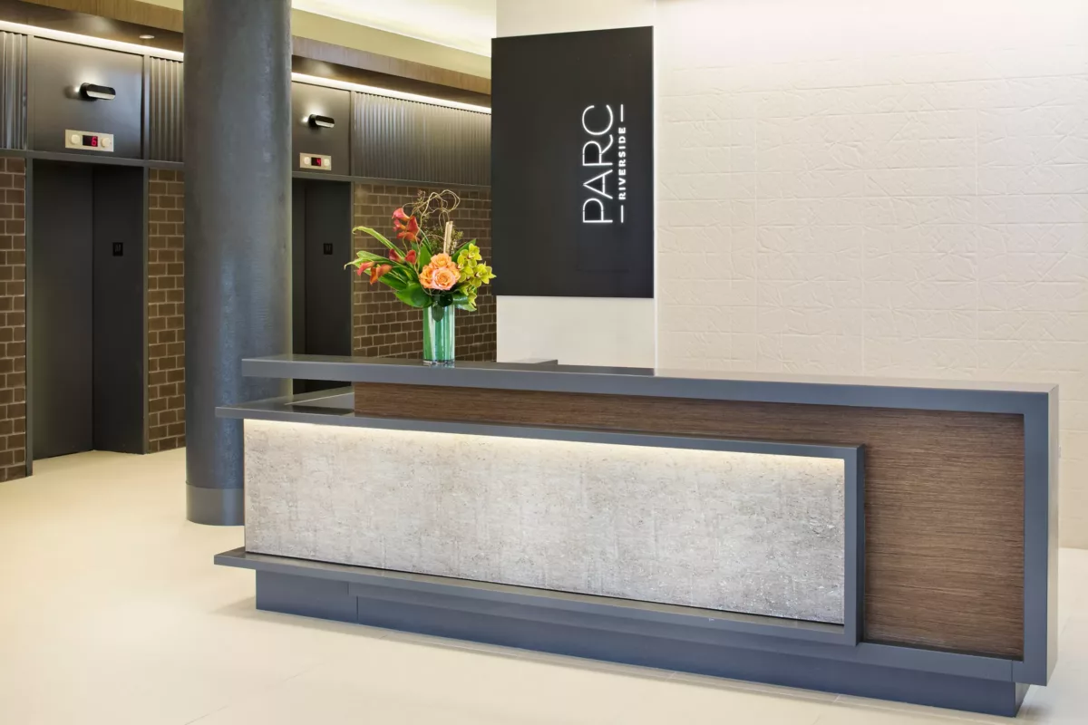 Modern lobby desk with stone front, wall signage, and minimalist decor.