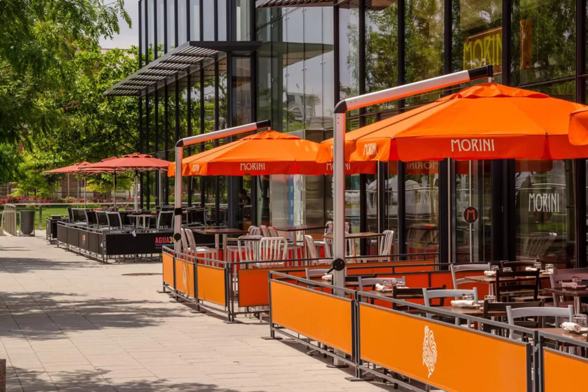 Outdoor patio dining with orange umbrellas and enclosed seating area.