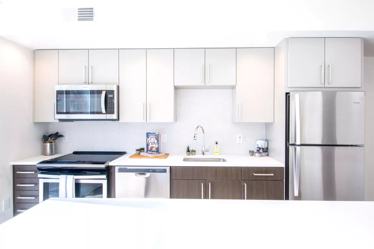 Modern kitchen with white upper cabinets, dark lower cabinets, and stainless appliances.
