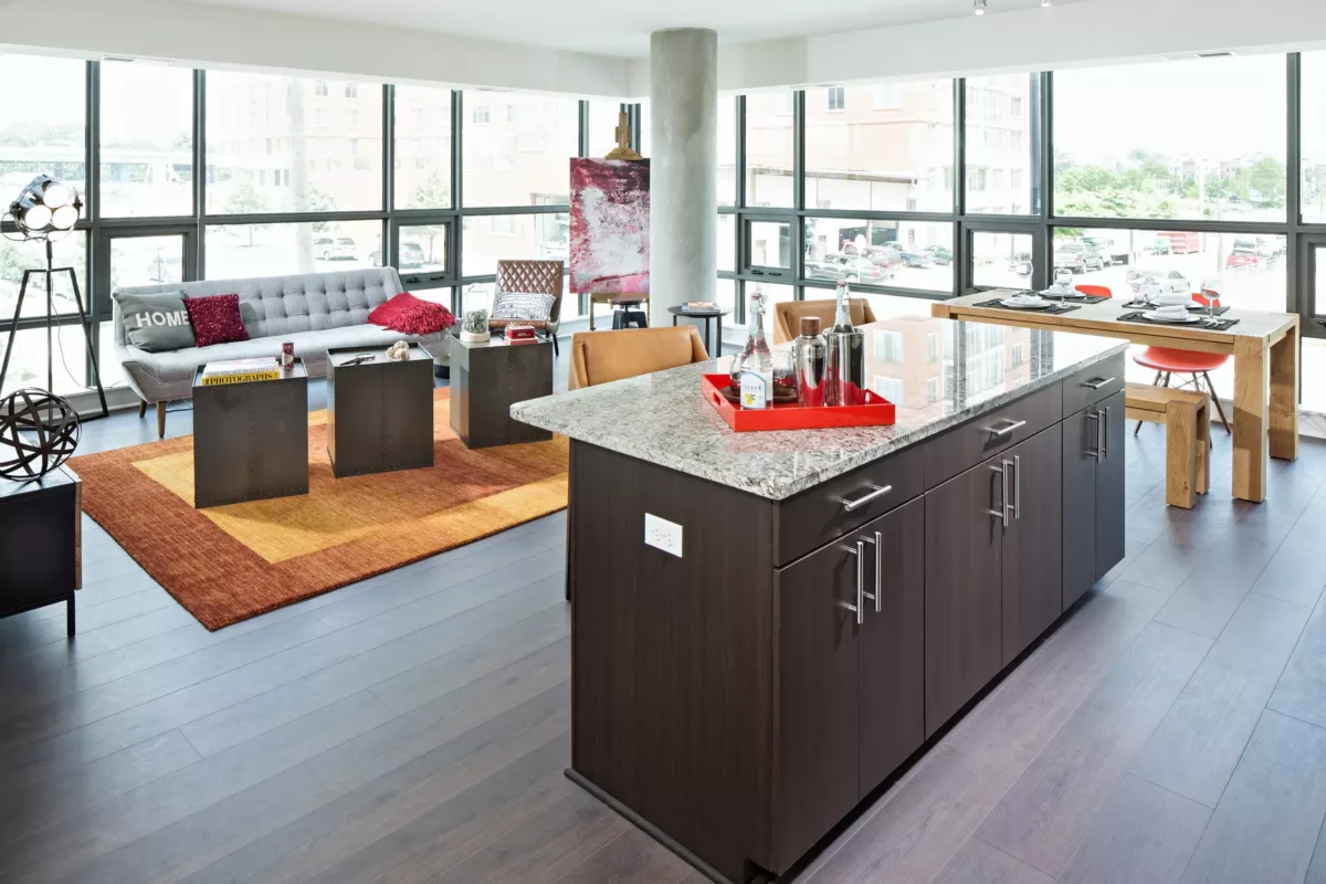 Open living area with kitchen island, seating, floor‑to‑ceiling windows, and city views.