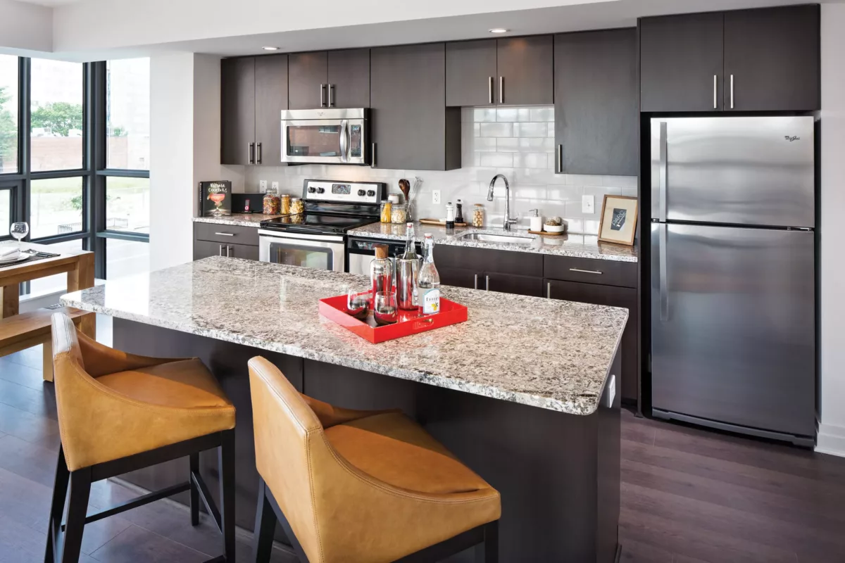 Kitchen with large island, granite countertop, stainless appliances, and bar seating.