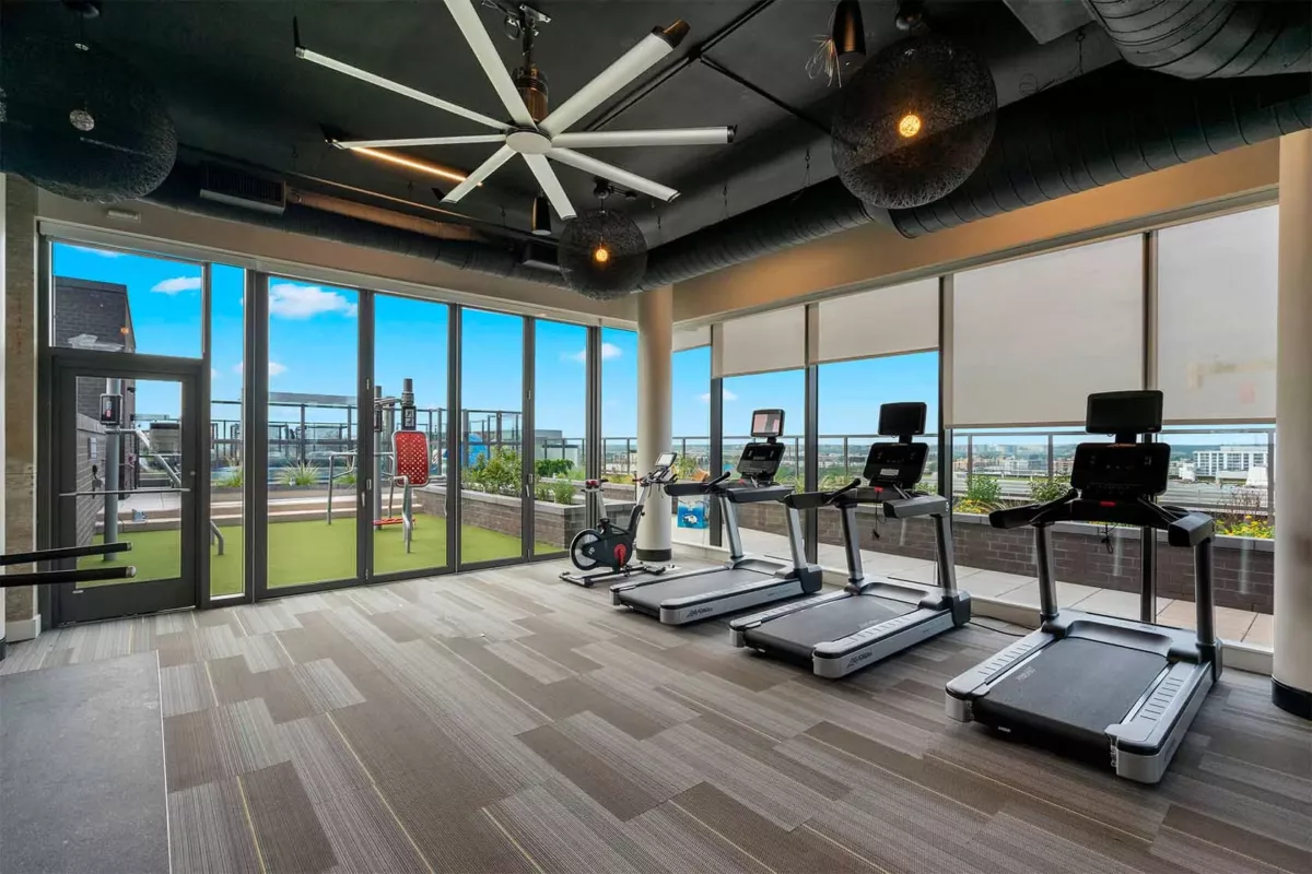 Indoor resident lounge with ceiling fan, seating areas, and floor‑to‑ceiling windows.