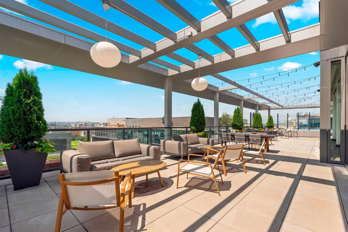 Rooftop patio with pergola, cushioned seating, tables, and open sky above.