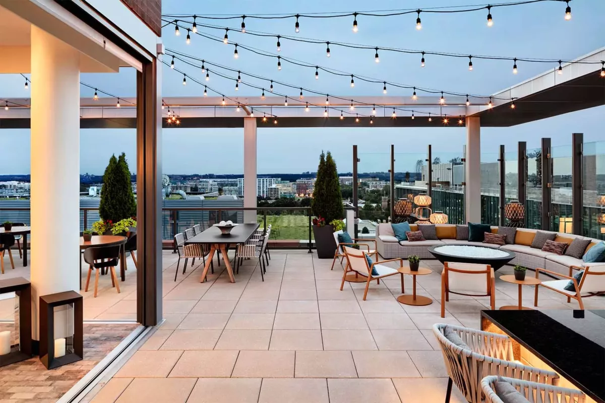 Rooftop lounge with string lights, bar seating, and open‑air views.